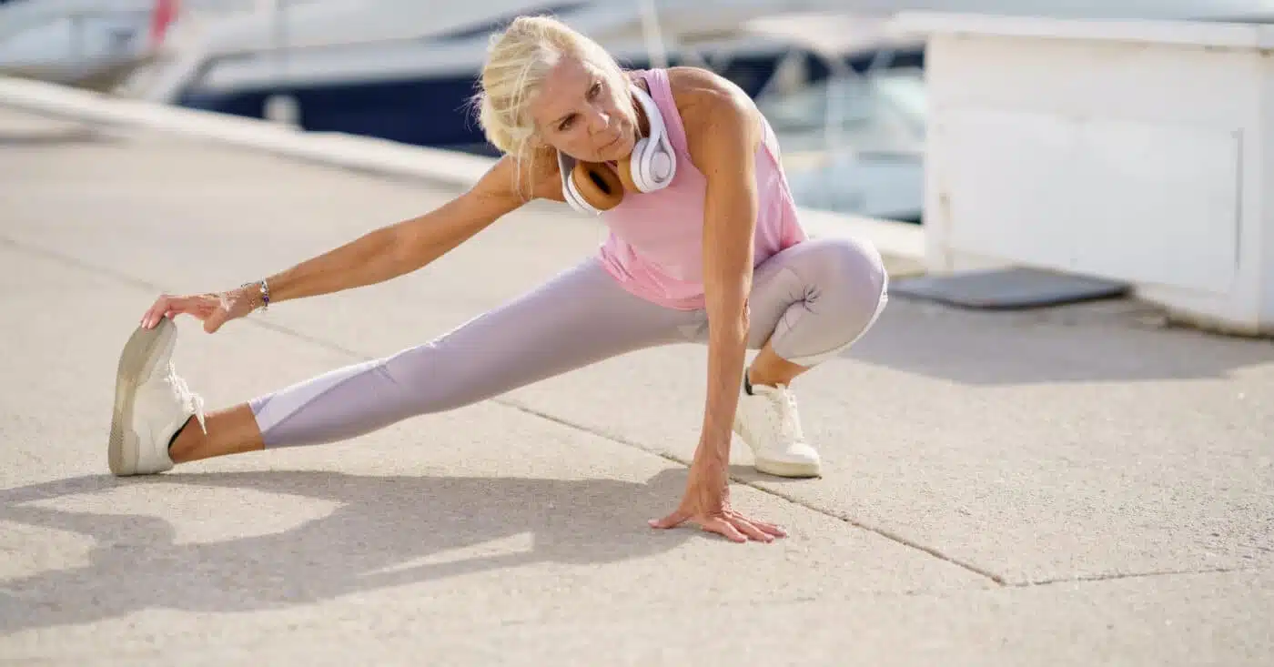 Une sportive âgée étire les jambes pendant l'entraînement